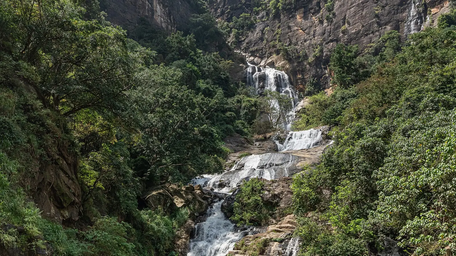 Wide view of the real Ravana Falls and forested rock escarpment near Ella, Sri Lanka