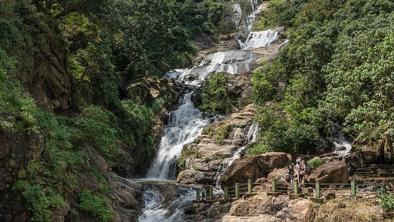 Travelers seen at a distance beside the real Ravana Falls in Ella, Sri Lanka
